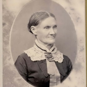 Cabinet-card portrait of Mary Elizabeth Gilmore Gore: an older woman in a dark bodice with a white lace jabot and brooch, hair centre-parted and drawn back.